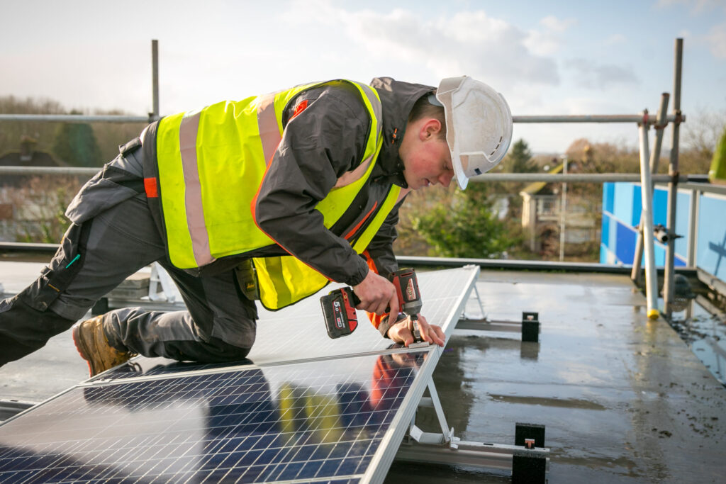 Engineer fixing solar panels on the roof of Liswerry High School, Newport, Gwent